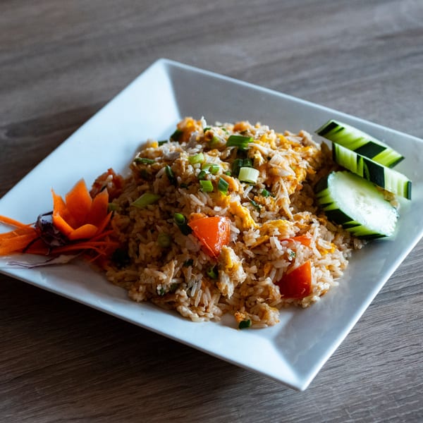 Kanda Thai Cuisine's crab fried rice with cucumber slices and a carrot garnish on a white plate.
